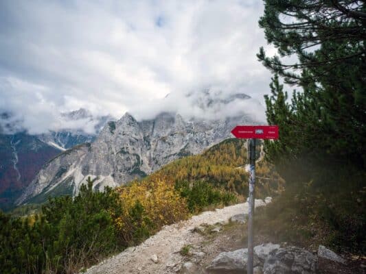 Berghüttenwegweiser mit malerischer Berglandschaft im Hintergrund.